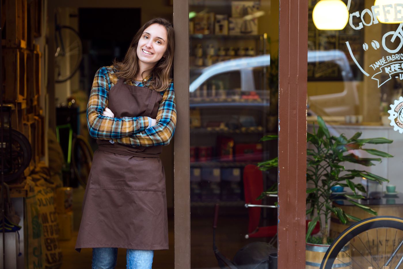 A woman standing in the entry way of her business' door.
