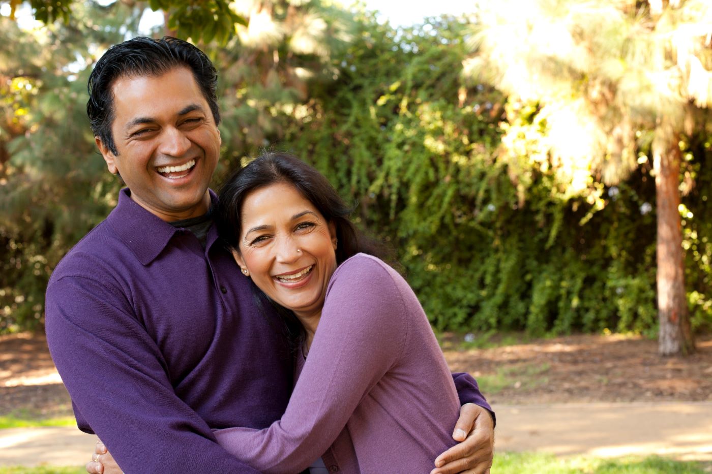 A middle-aged couple hugging each other and laughing.